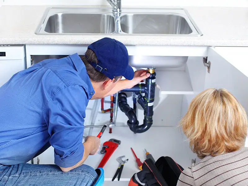 Professional plumber using a pipe wrench to repair under-sink drainage pipes in Hatfield Hertfordshire
